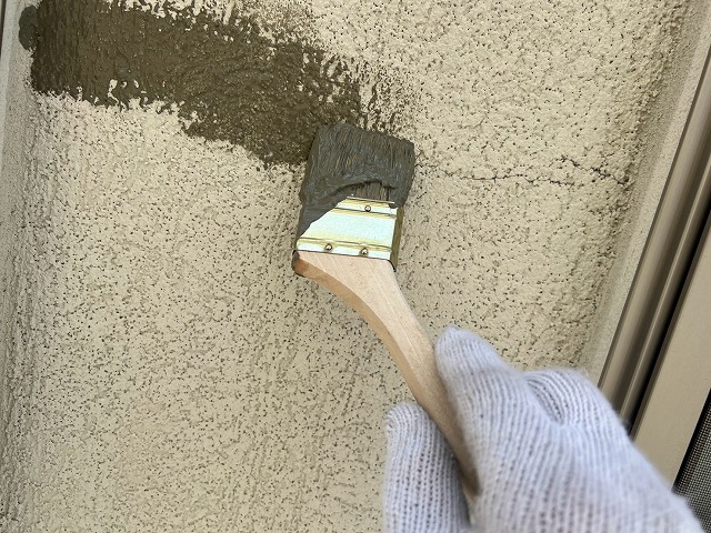 ひび割れに刷毛で樹脂モルタルを刷り込んで補修している様子