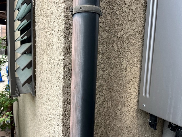 日焼けして上部だけ色が抜けた縦樋と外壁に残る雨筋の跡