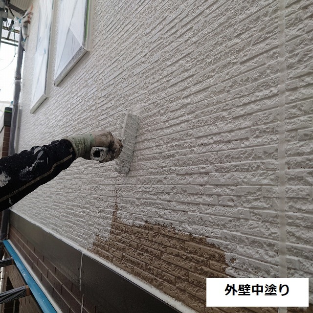 上部の壁面にベージュの中塗りを塗り広げる様子