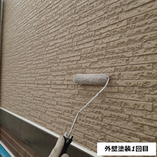 上部の外壁にシーラーを塗り広げる様子