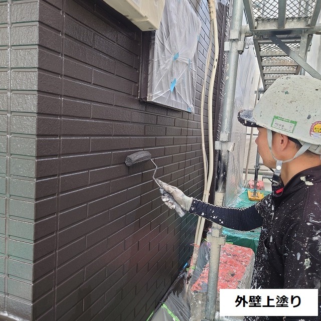 濃い茶色の上塗りをローラーで仕上げる作業