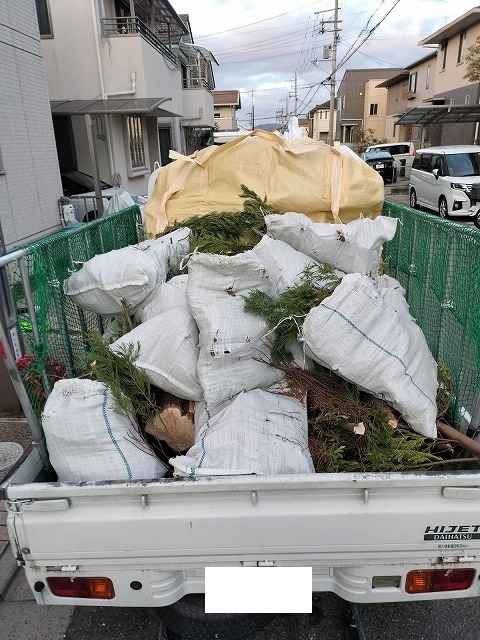 伐採した庭木を土のう袋に詰め、軽トラックに積んで処分場へ運ぶところ
