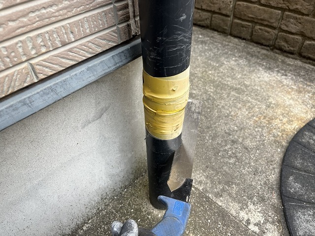 塩ビ管用のこぎりで竪樋の割れた部分の下側を水平に切断しているところ