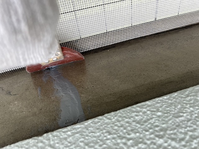 ゴムベラで充填したパテを平らに均す作業