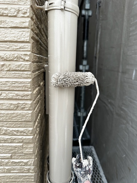 色あせしていた雨樋をローラーで塗装している様子