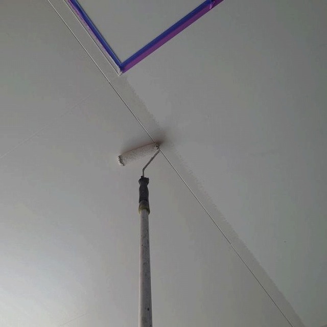 軒天の入隅をローラーで塗り込んでいる様子
