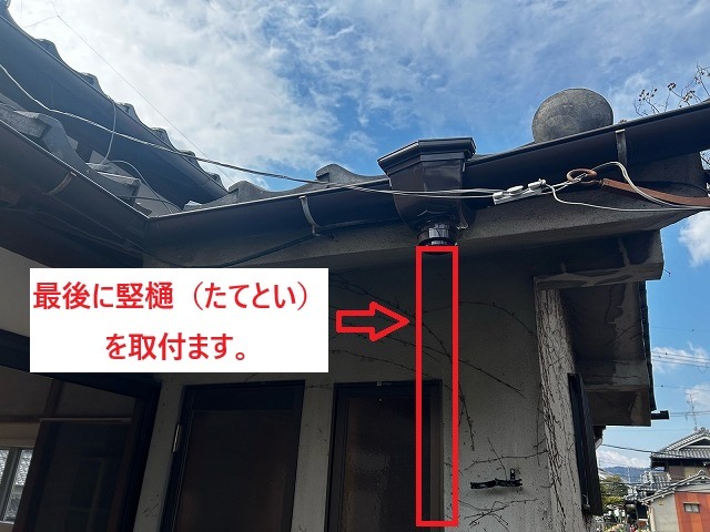 集水器の下に新しい竪樋を差し込んで取り付けているところ