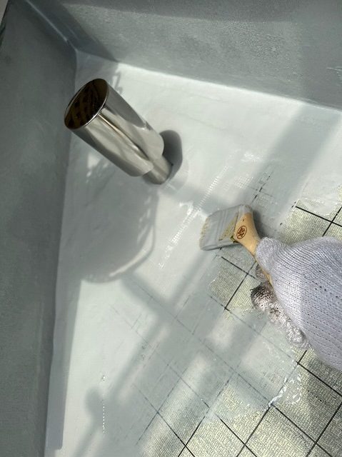 取り付けた脱気筒の周囲にウレタン防水材を刷毛で塗り込む作業