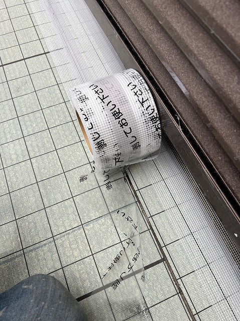 通気緩衝シートの継ぎ目に末端テープを貼り付けて処理する作業