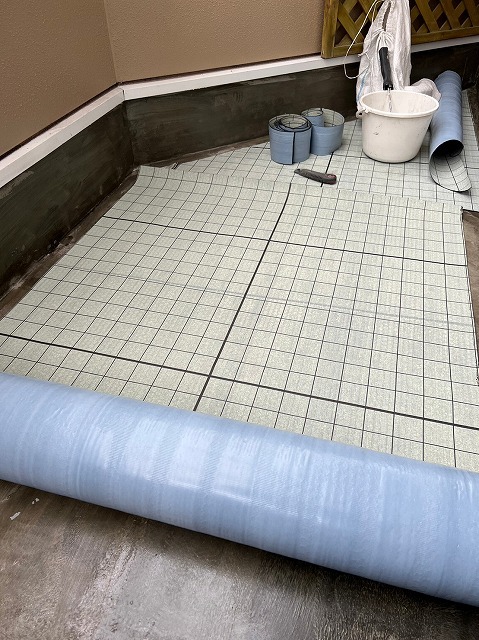 通気緩衝シートのロールと敷き込みを進めているベランダ床