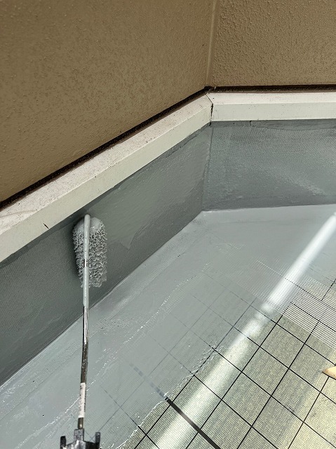 長柄ローラーでウレタン防水材の1回目を平場に塗り広げる工程