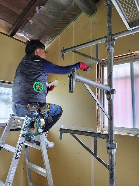 室内の壁の継ぎ目にファイバーテープを貼る作業