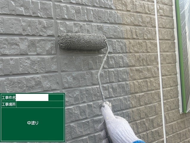 ローラーで外壁の中塗りを行いレンガ調の凹凸に塗料を送り込む作業