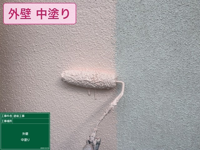 淡いピンクの塗料で外壁の中塗りを施工中