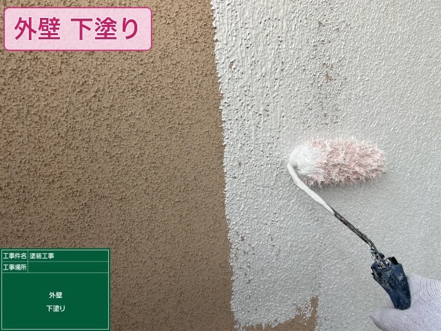 モルタル外壁に白い下塗り材を塗布している様子