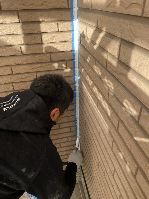 職人がヘラでシーリング材を押さえて仕上げる作業