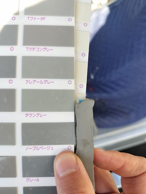 切り取った既存シーリングをカラーサンプルに当てて色を合わせる作業