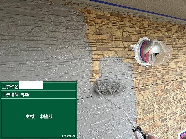積み石調サイディングに中塗りを塗り進めているところ