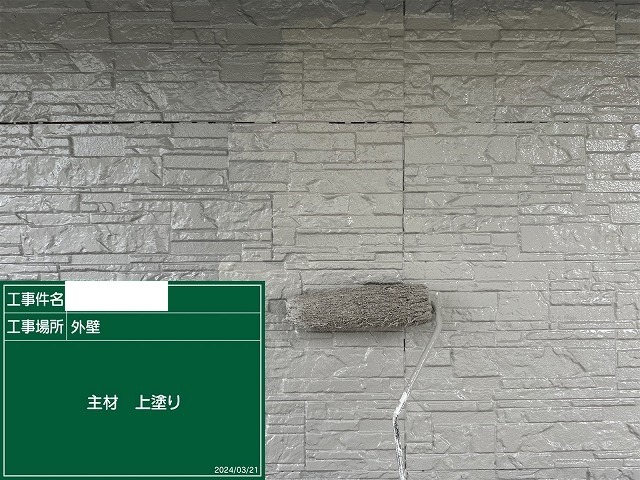 積み石調サイディングに上塗りをローラーで仕上げているところ