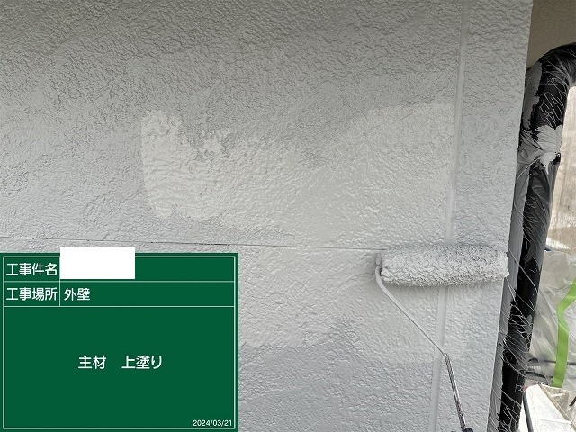 細かい凹凸のあるサイディング面を上塗りで仕上げているところ