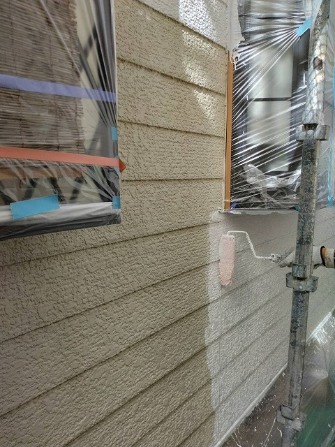 外壁の下塗り。白い下塗り材をローラーで塗り広げ、下地の色を均一に止めていく 外壁の下塗り。白い下塗り材をローラーで塗り広げ、下地の色を均一に止めていく
